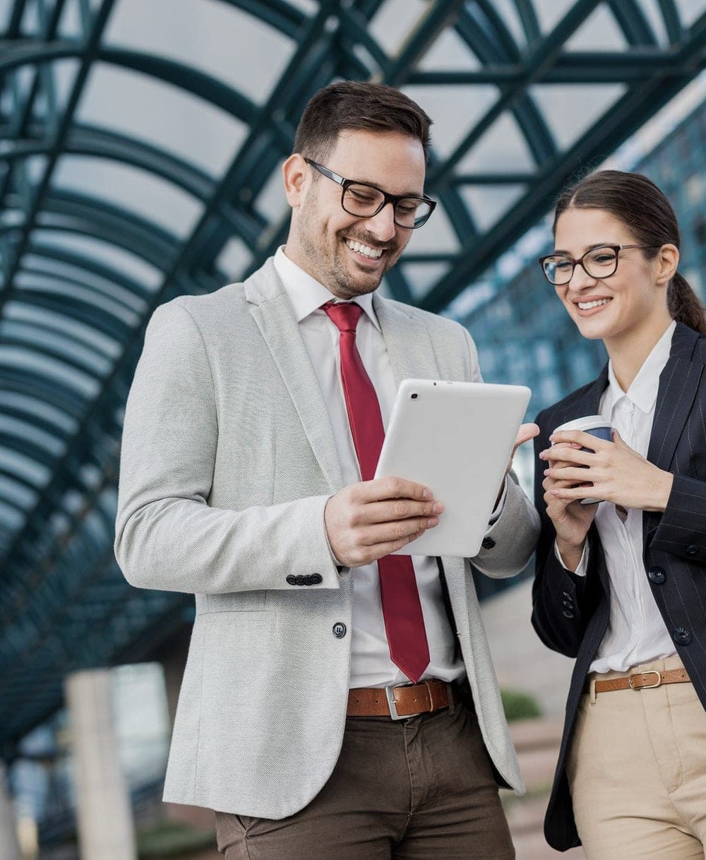 Two colleagues sharing a tablet in a glass-roofed office atrium